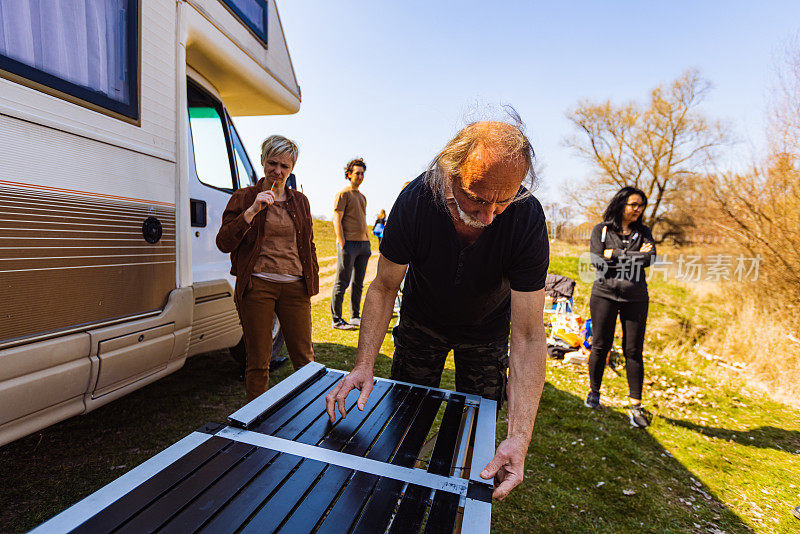 Mid-adult Caucasian man preparing outdoor table and chairs for family camping